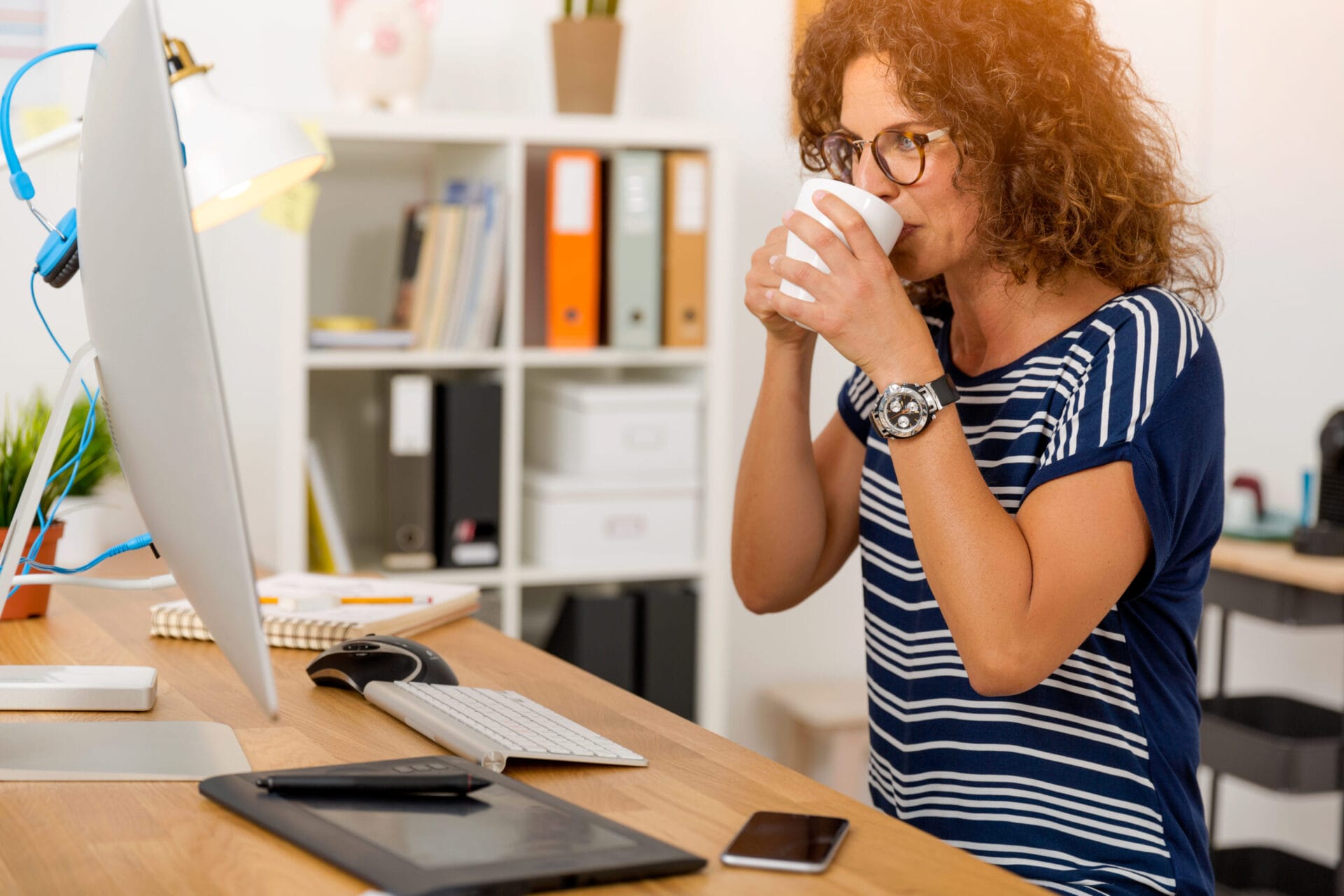 Middle aged woman working on the office and drinking coffee