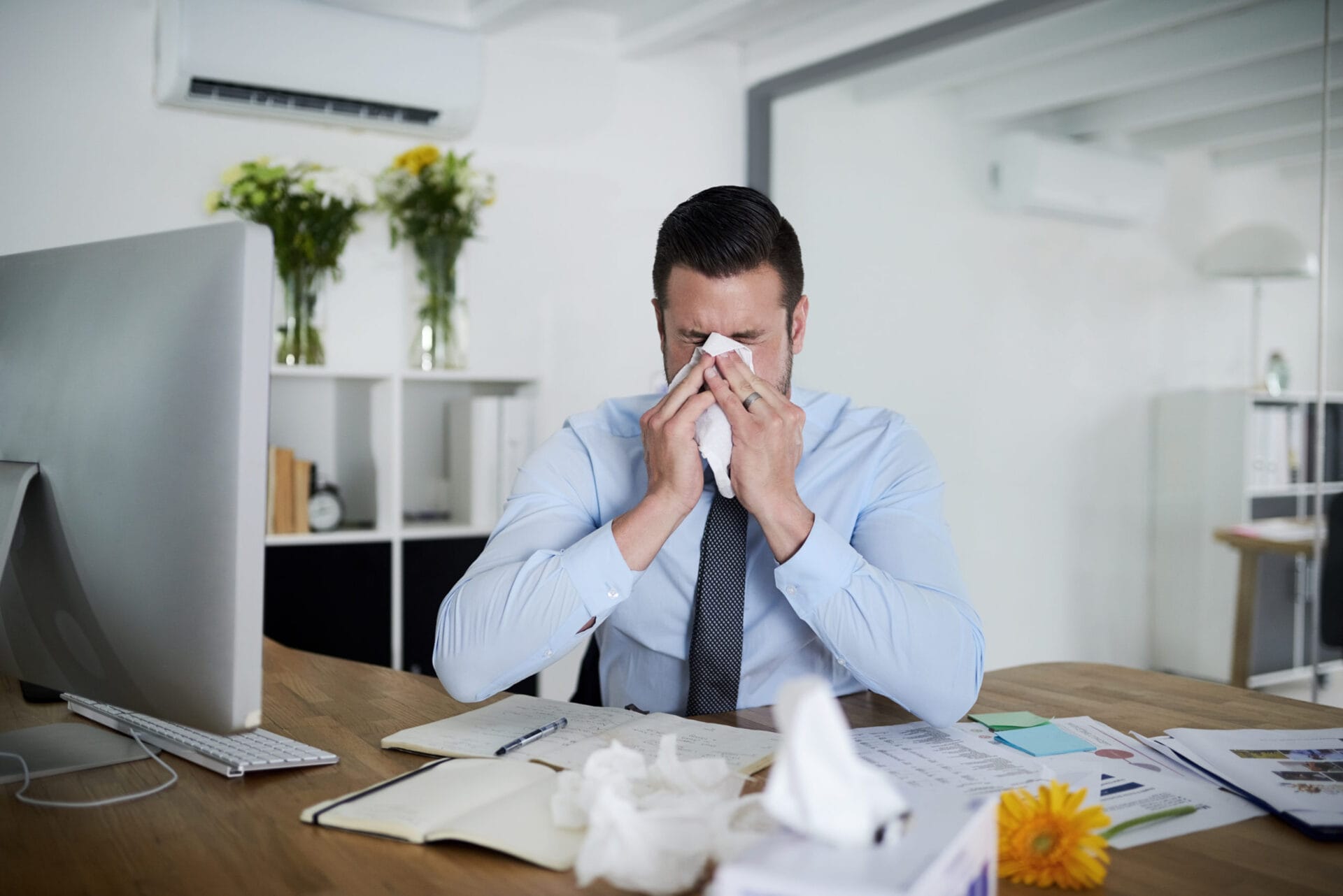 No sick days left. Shot of a young businessman suffering with allergies at work