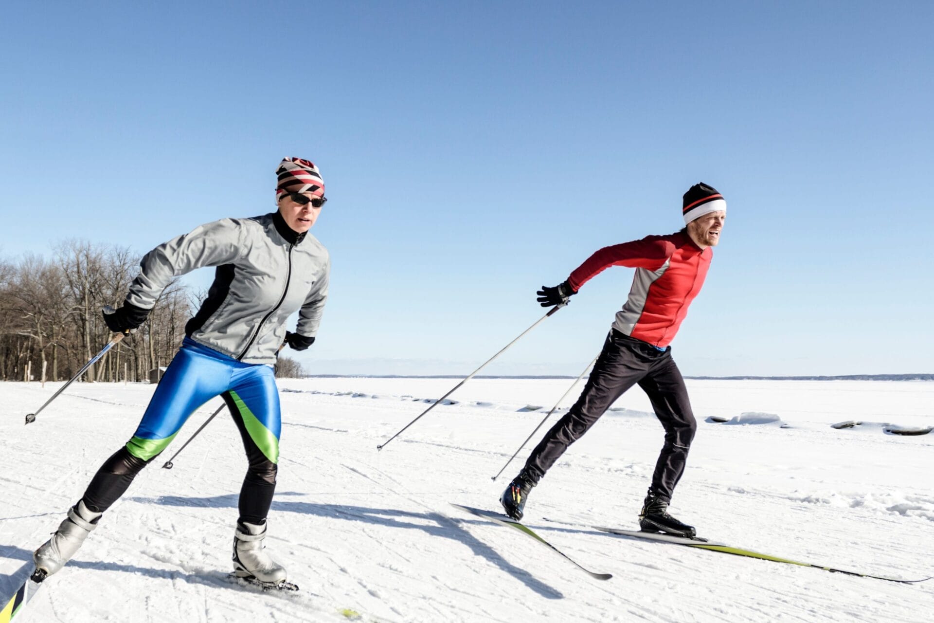 Male and female athletes cross-country skiing on a sunny day.