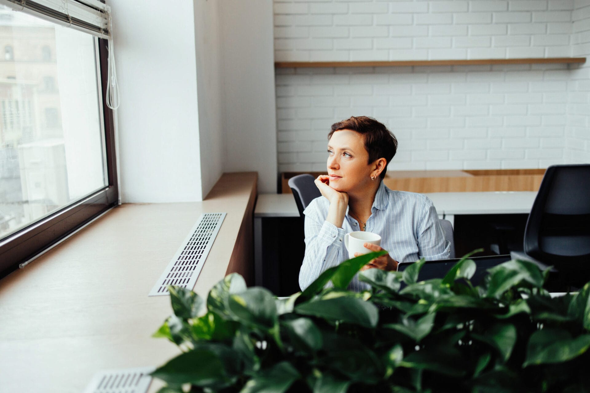 A woman sits at a table in a modern office and communicates on a smartphone