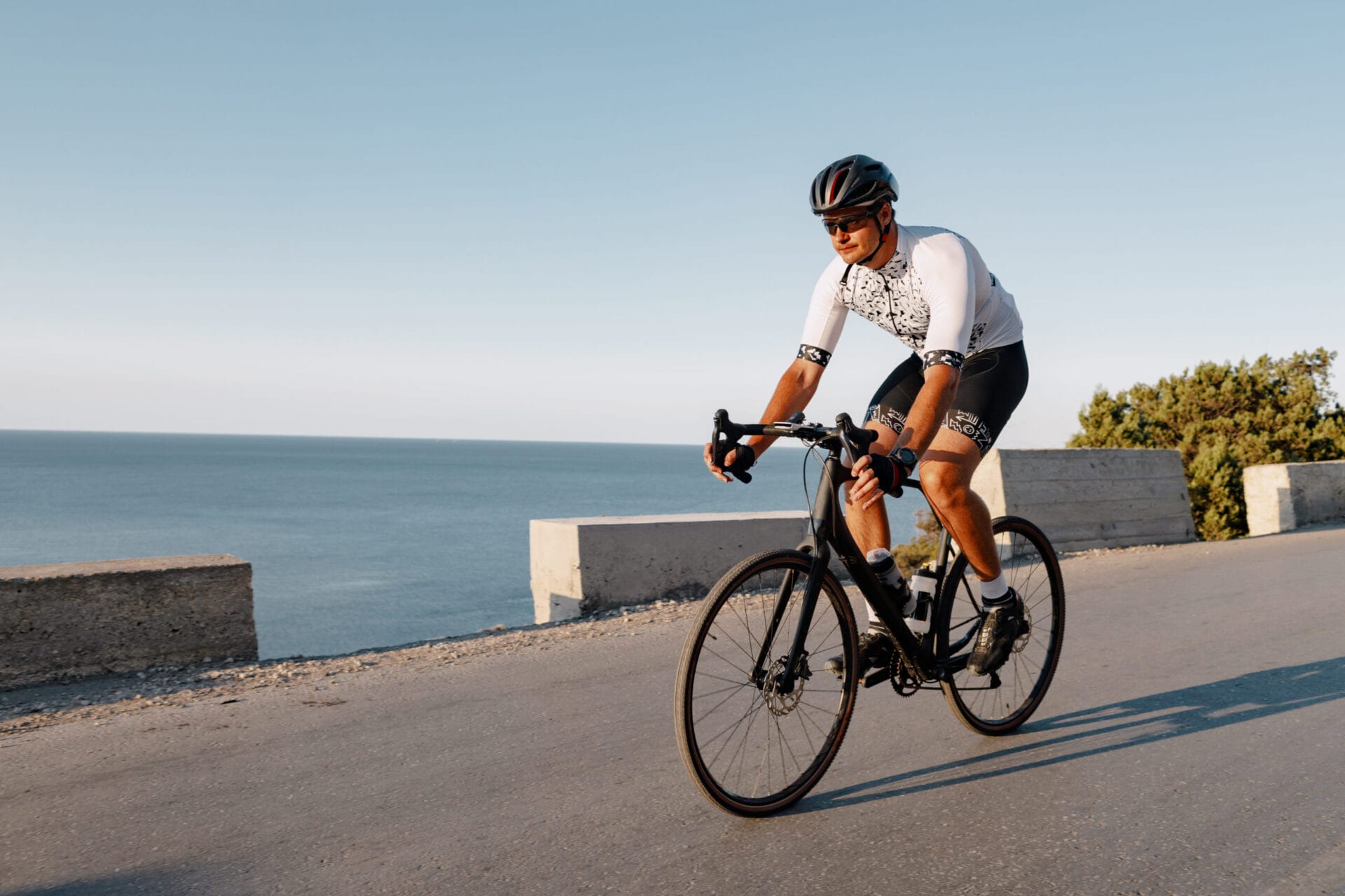 Cycling sport athlete man riding on coastal road at dawn