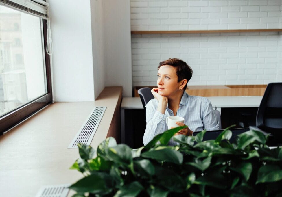 A woman sits at a table in a modern office and communicates on a smartphone