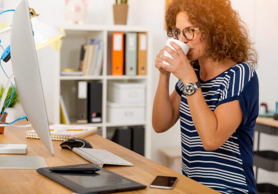 Middle aged woman working on the office and drinking coffee