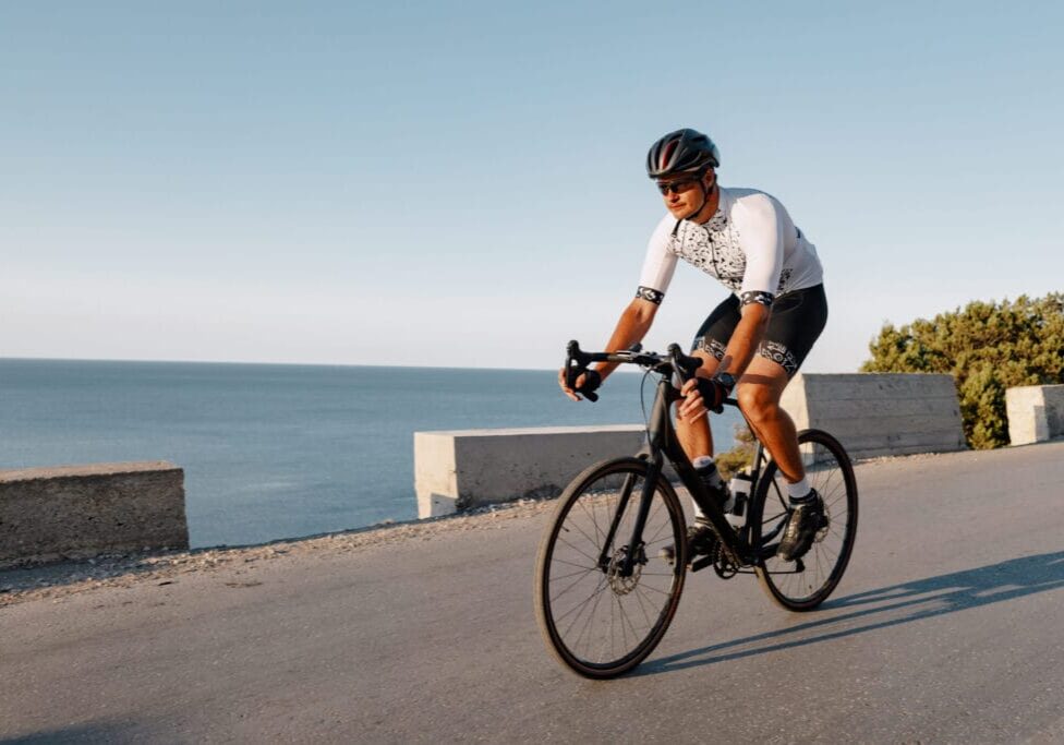 Cycling sport athlete man riding on coastal road at dawn