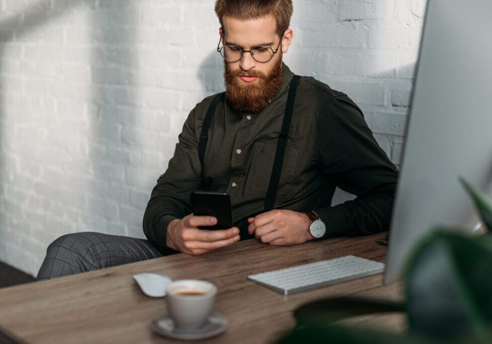 handsome businessman sitting and using smartphone in office