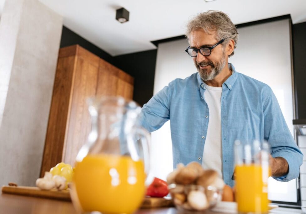 Elderly man is preparing some healthy food in his kitchen