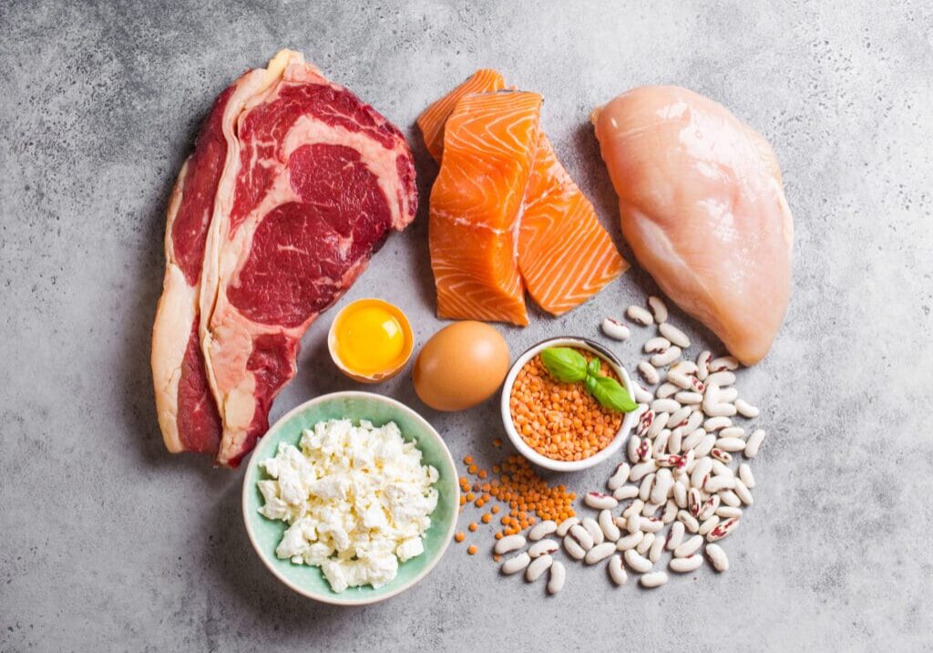 Assortment of natural sources of protein from food: meat, fish, chicken, dairy products, eggs, beans. Diet, healthy eating, wellness, bodybuilding concept, top view, stone background