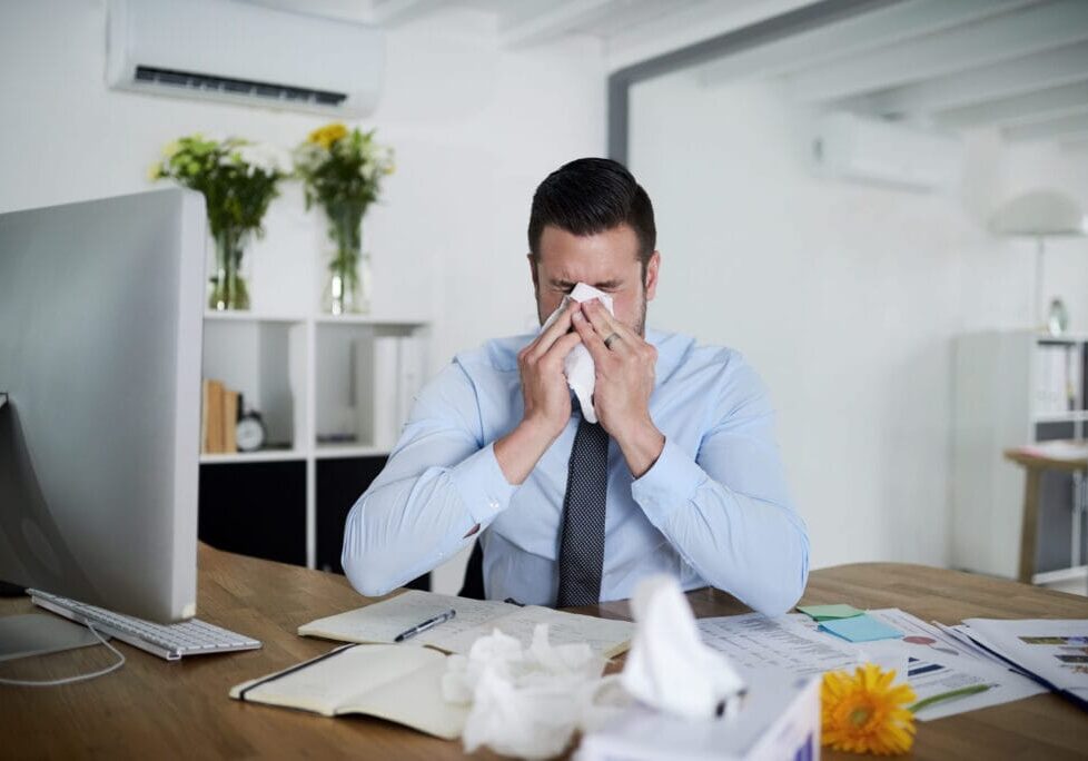 No sick days left. Shot of a young businessman suffering with allergies at work