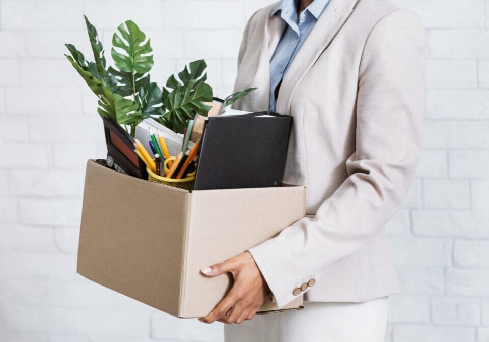 Unrecognizable black woman holding box of personal belongings, leaving office after losing her job, closeup of hands. Economic crisis and unemployment during covid-19 epidemic